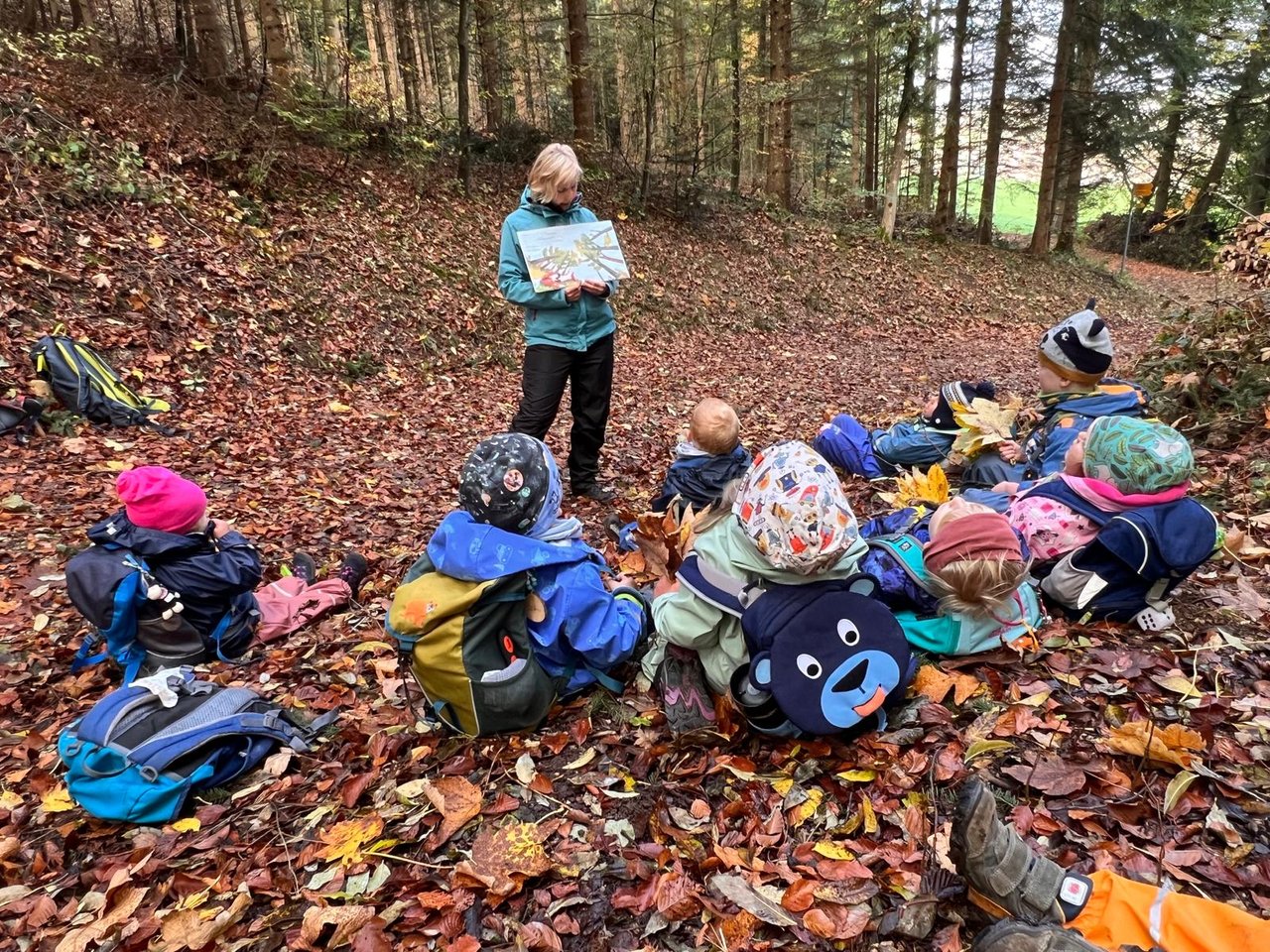Spielgruppenleiterin bespricht mit Kindern den Weg im herbstlichen Wald