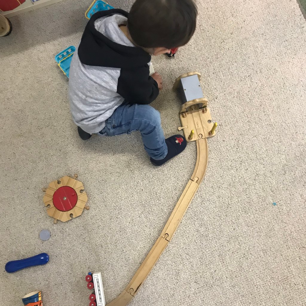 Kind spielt mit einer Holzeisenbahn