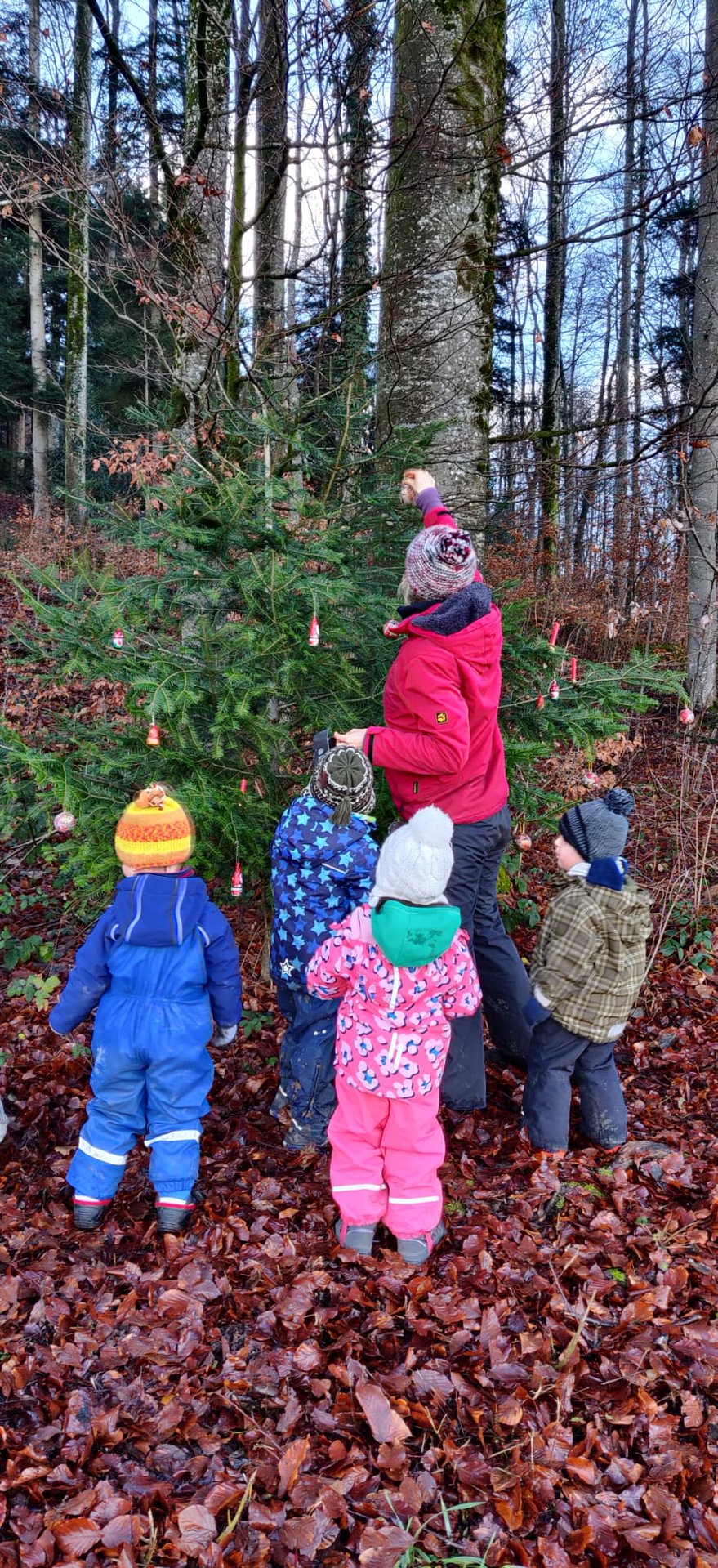 Kinder stehen im Kreis mitten im winterlichen Wald